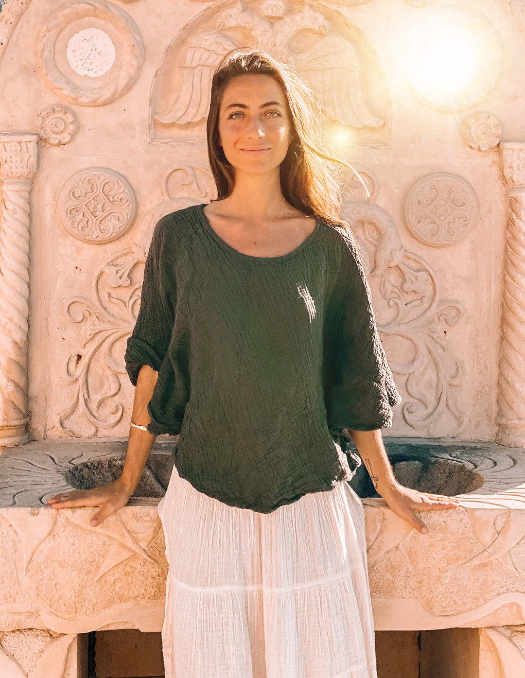Woman has on green poncho top with white skirt