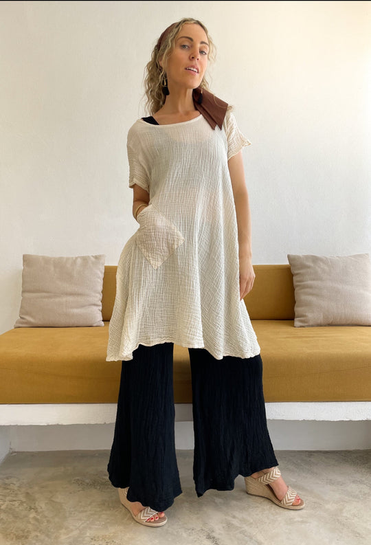 Woman layers shorter dress with long blousy pants and sandals.