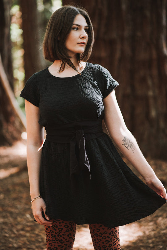 Model has on short-sleeve black textured dress and leopard leggings.