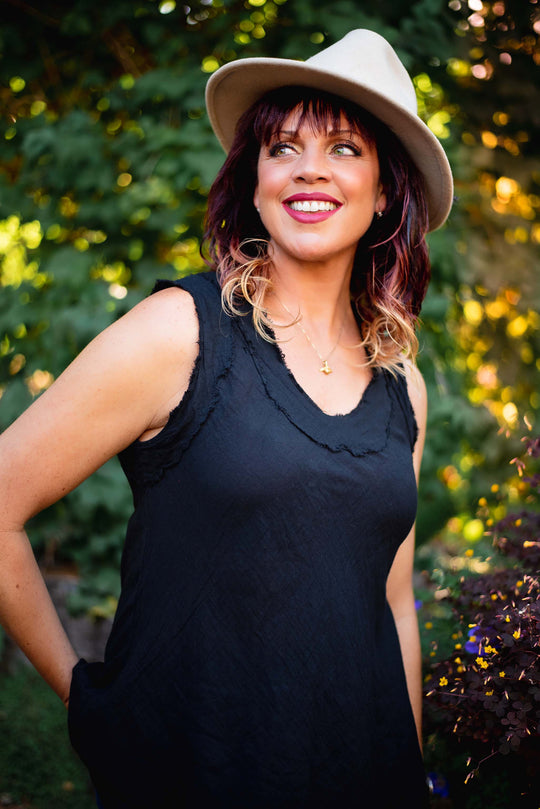 Woman smiles wearing brown hat and black tank top.