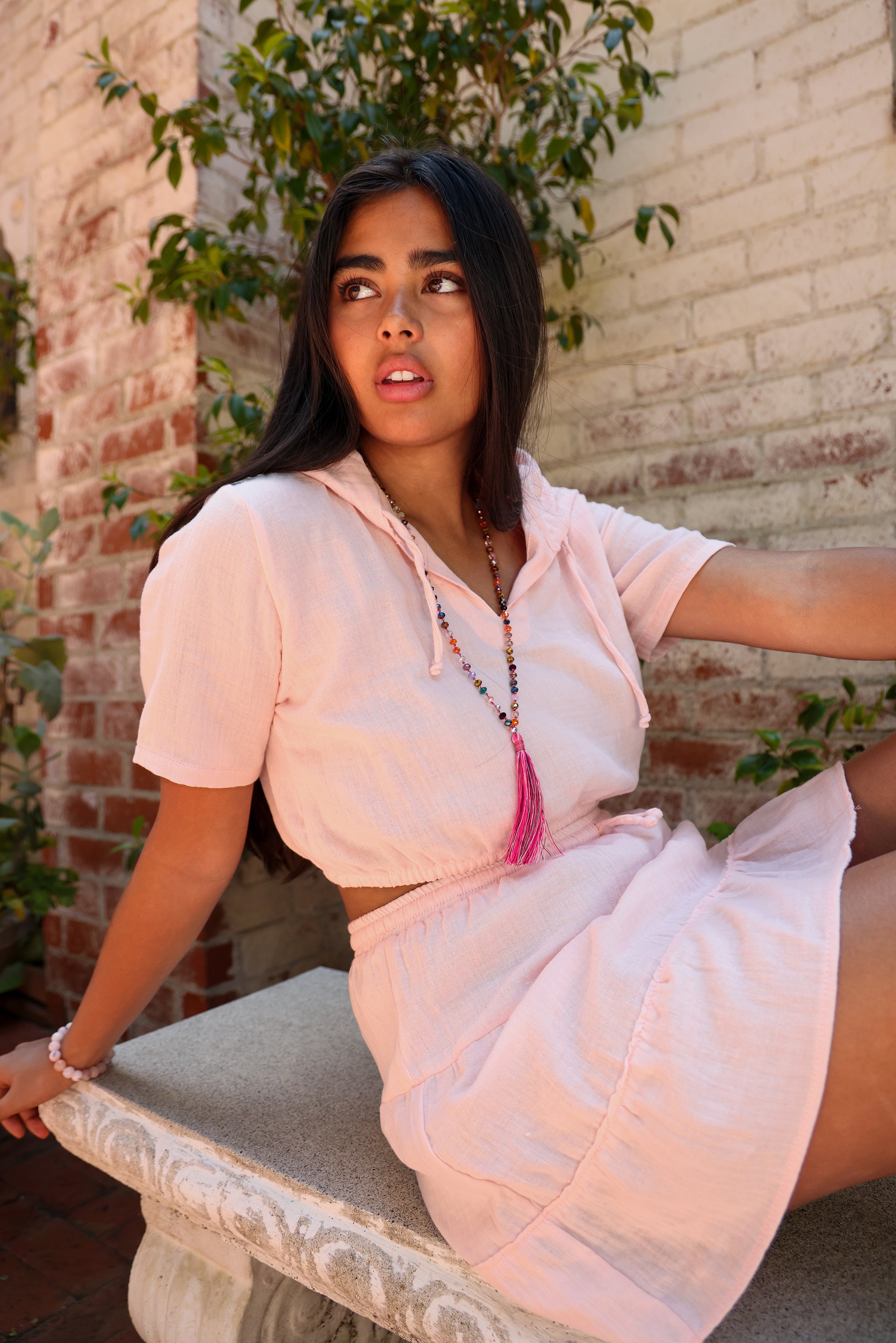 Model wears pink cropped hooed with matching mini skirt.