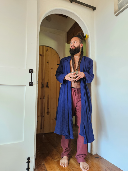 Man stands in doorway wearing blue robe and lounge pants.