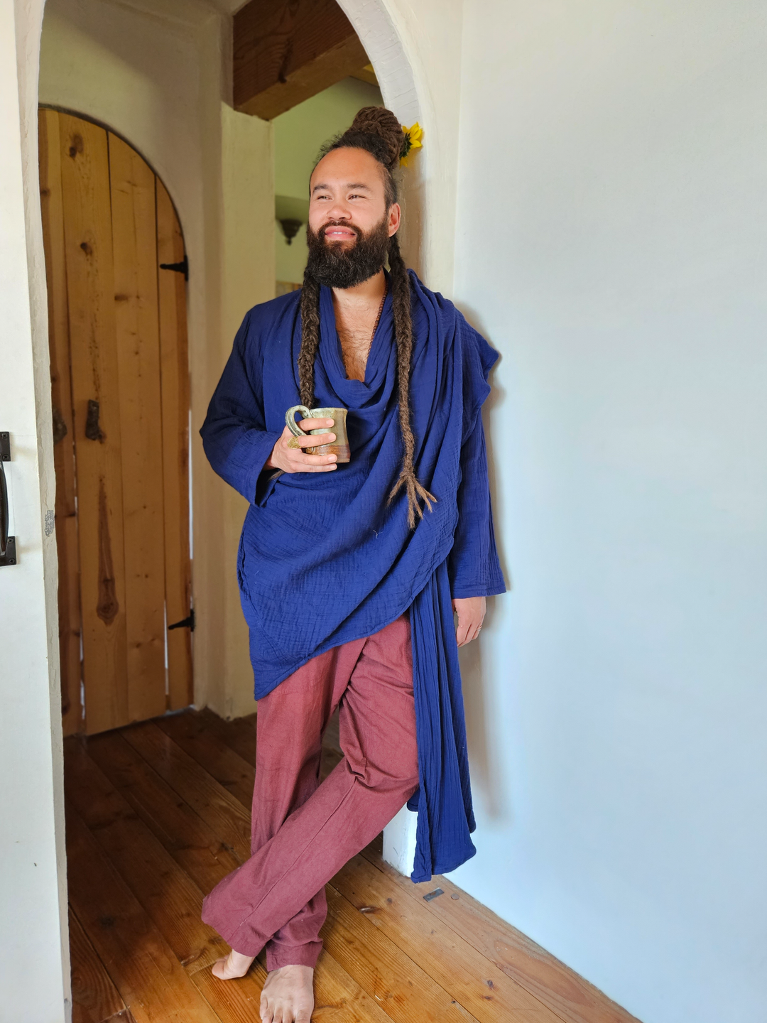 Man is wearing blue cloak wrapped around his upper body and pants on bottom.