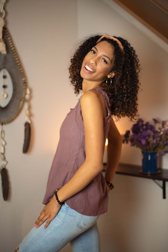 Female model shows off purple tank top paired with jeans.