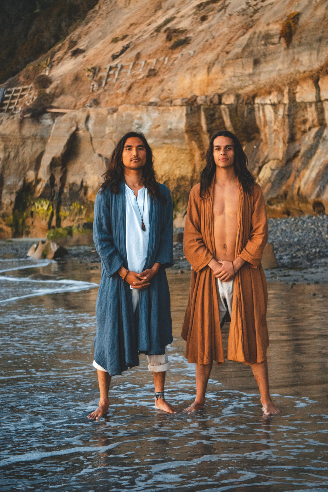 Two male model don long robes at the beach.