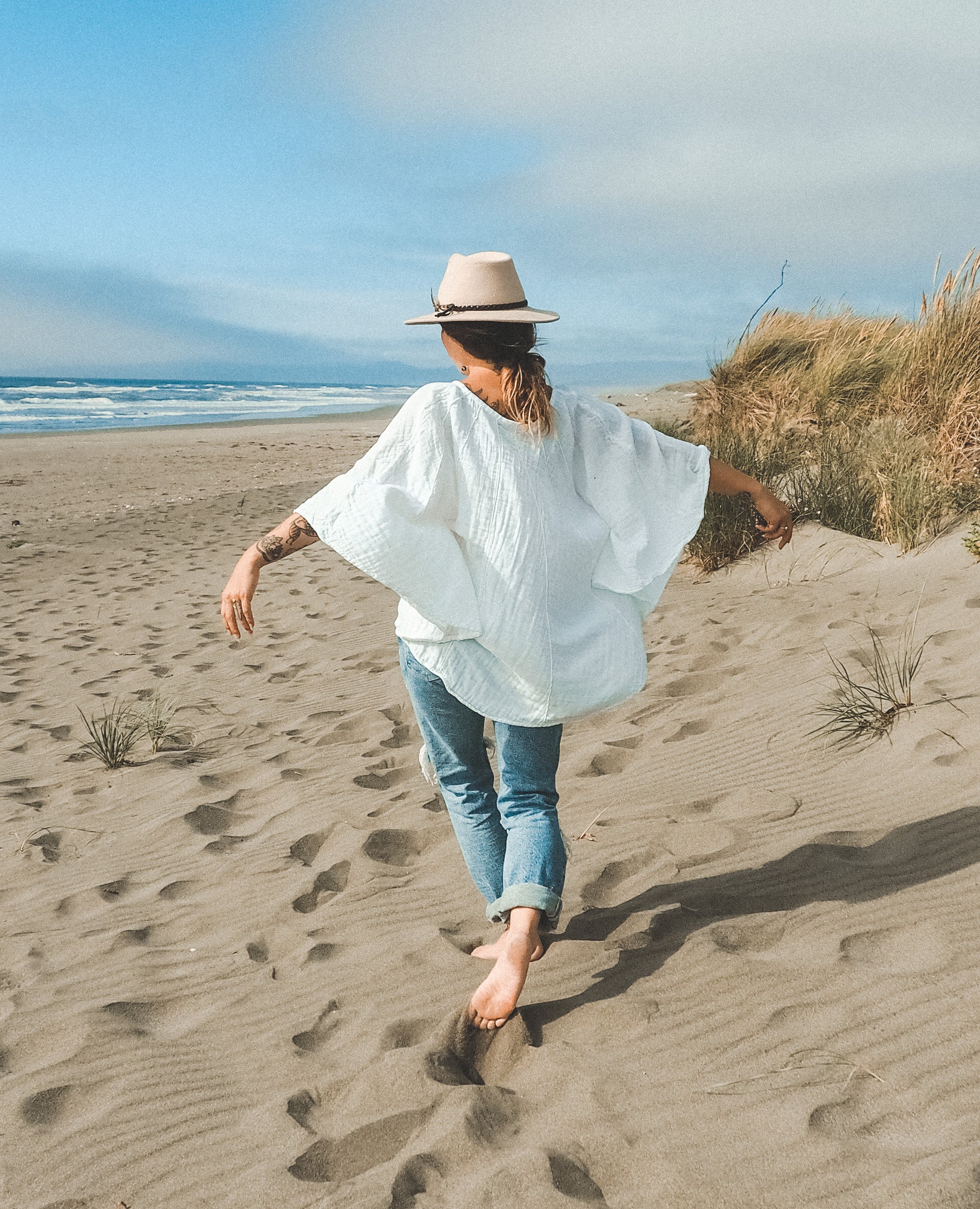 Woman on beach in white gauze cotton spirit poncho top