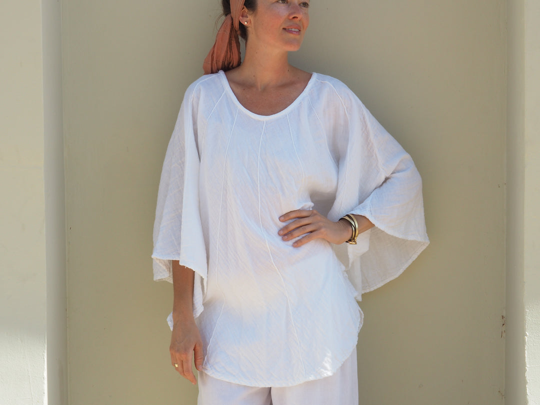 Female model poses in lightweight white shirt and pants.