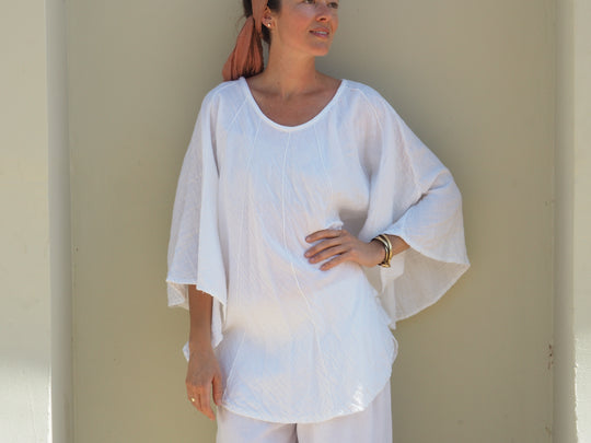 Female model poses in lightweight white shirt and pants.