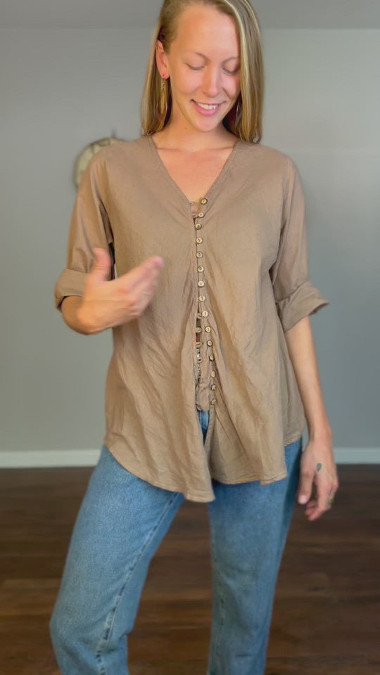 Woman models a button shirt. She walks in, shows how to tie the shirt tails, and walks out.