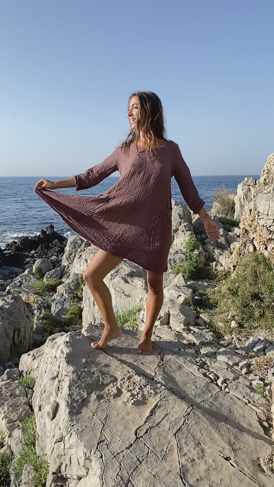 Woman shows off fabric and texture of tunic dress. Her legs are bare.