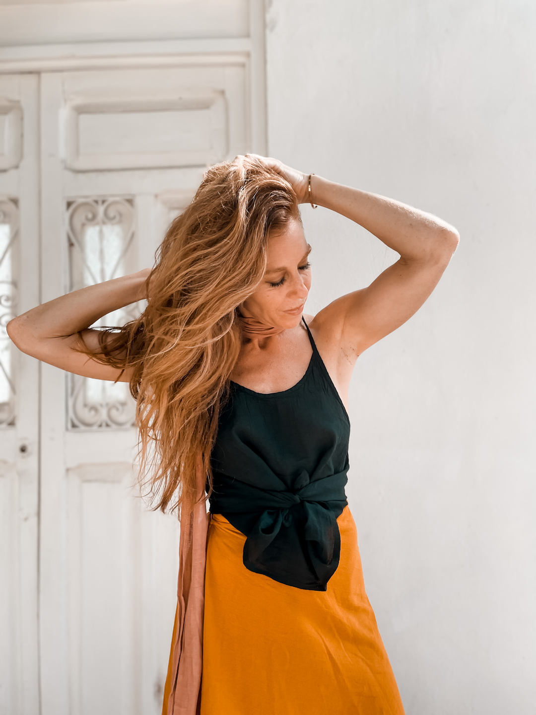 Model has black camisole tied in front  and long fold skirt.