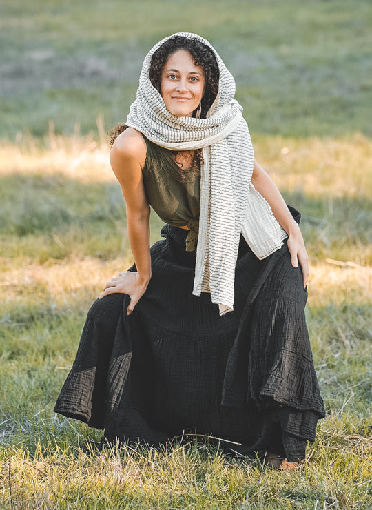 Model has on tied green top, textured skirt and striped head scarf.