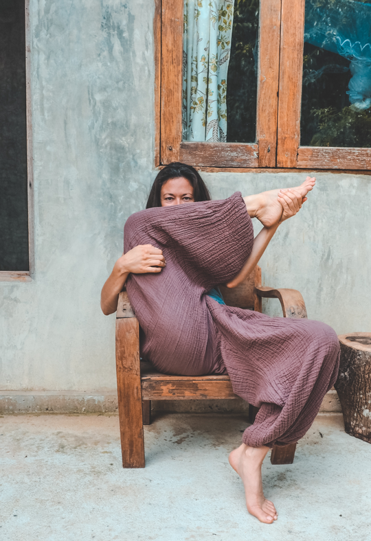 Woman sits in chair showing off purple gauze lounge pants.