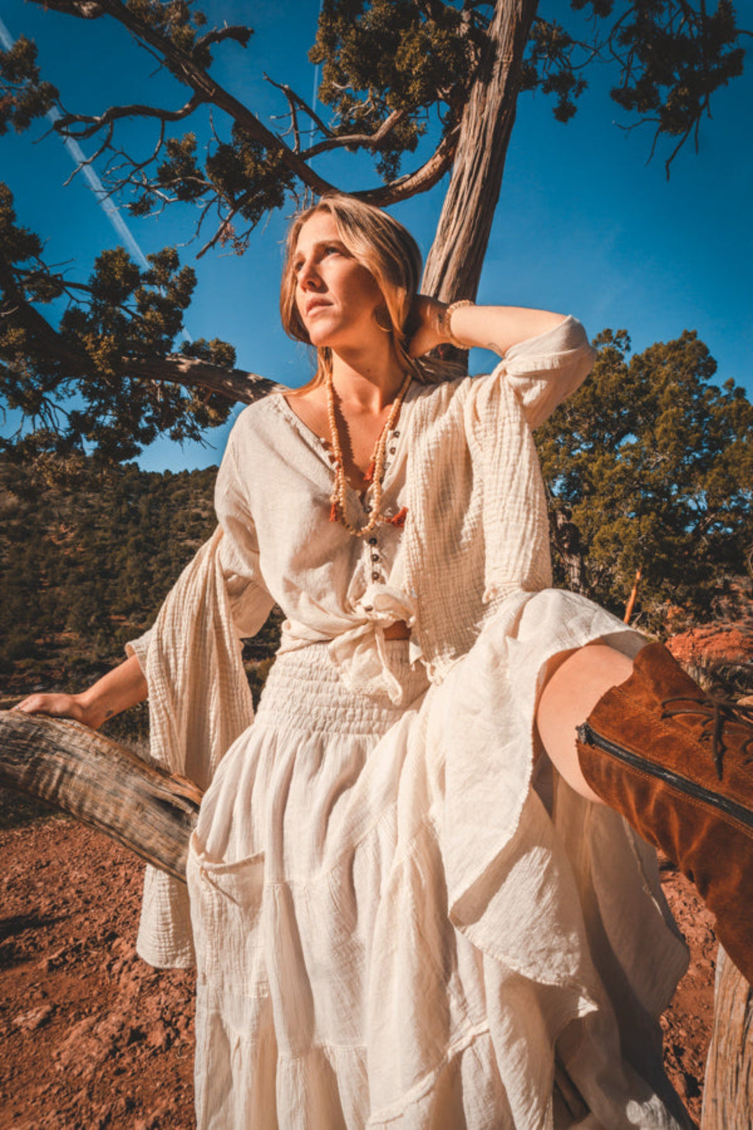 Model is dressed in un-dyed natural button top and long gauze skirt. She perches on a tree limb.