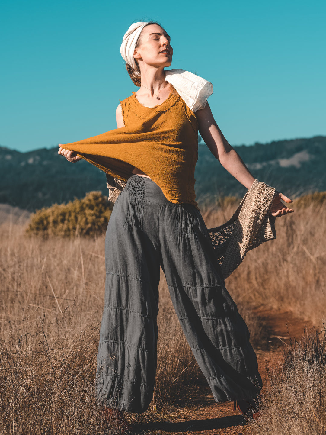 Model in tall grass wears flowy gauze clothing