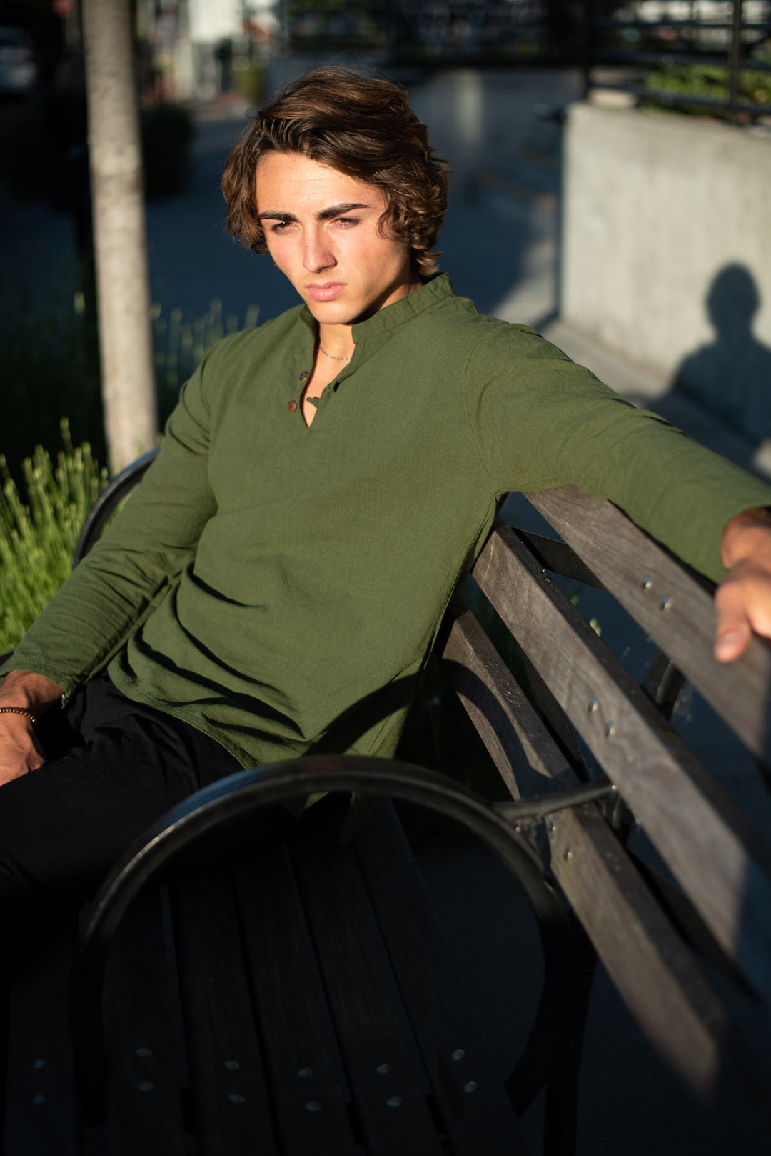 Model leans against bench in a long-sleeve dress shirt.