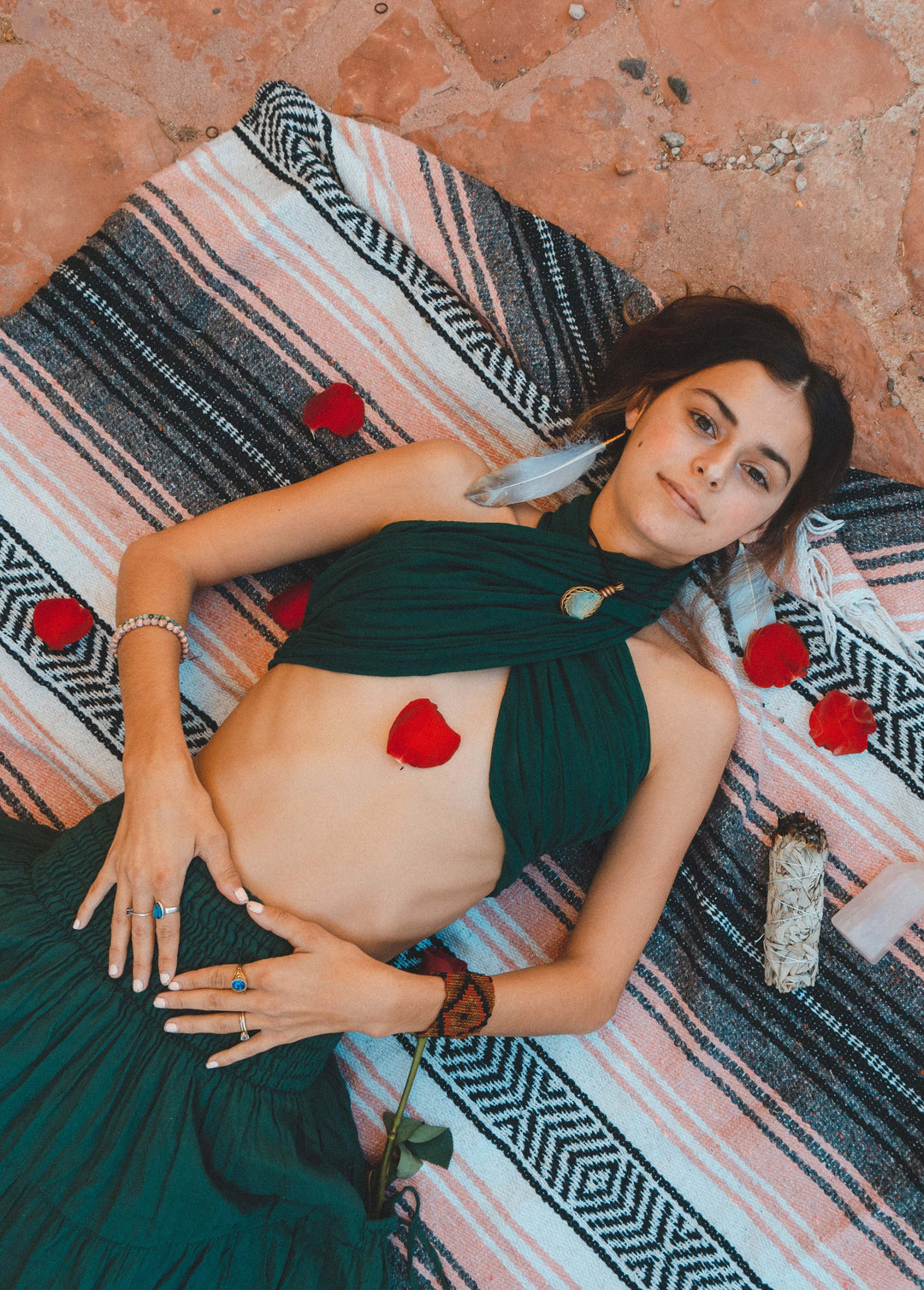 Woman shows off long scarf tied as a bikini top with long skirt. She lays on a blanket.