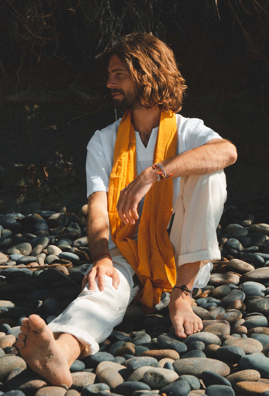 Man wearing gold cotton scarf draped around neck.