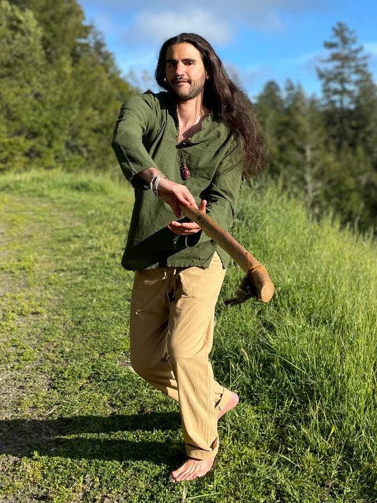 Barefoot model has on long-sleeve green shirt and khakis.