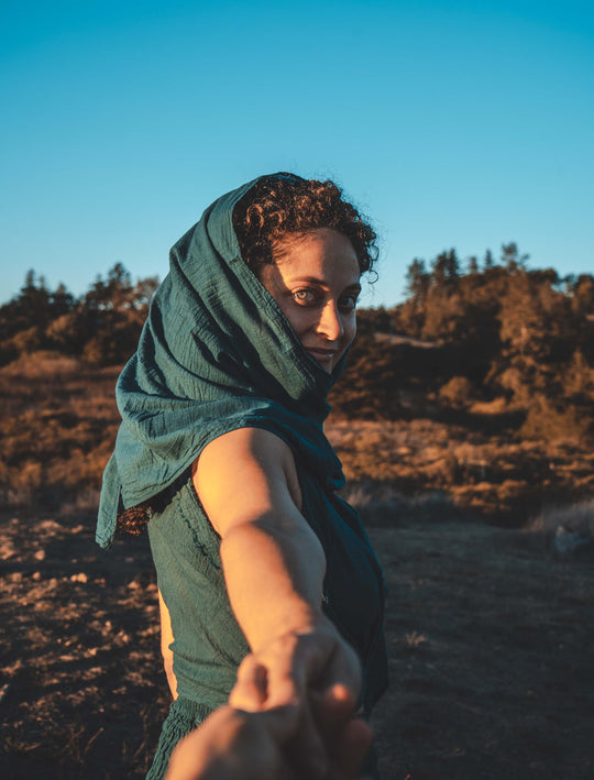 Woman has hair adorned in long green gauze scarf with matching tank and skirt.