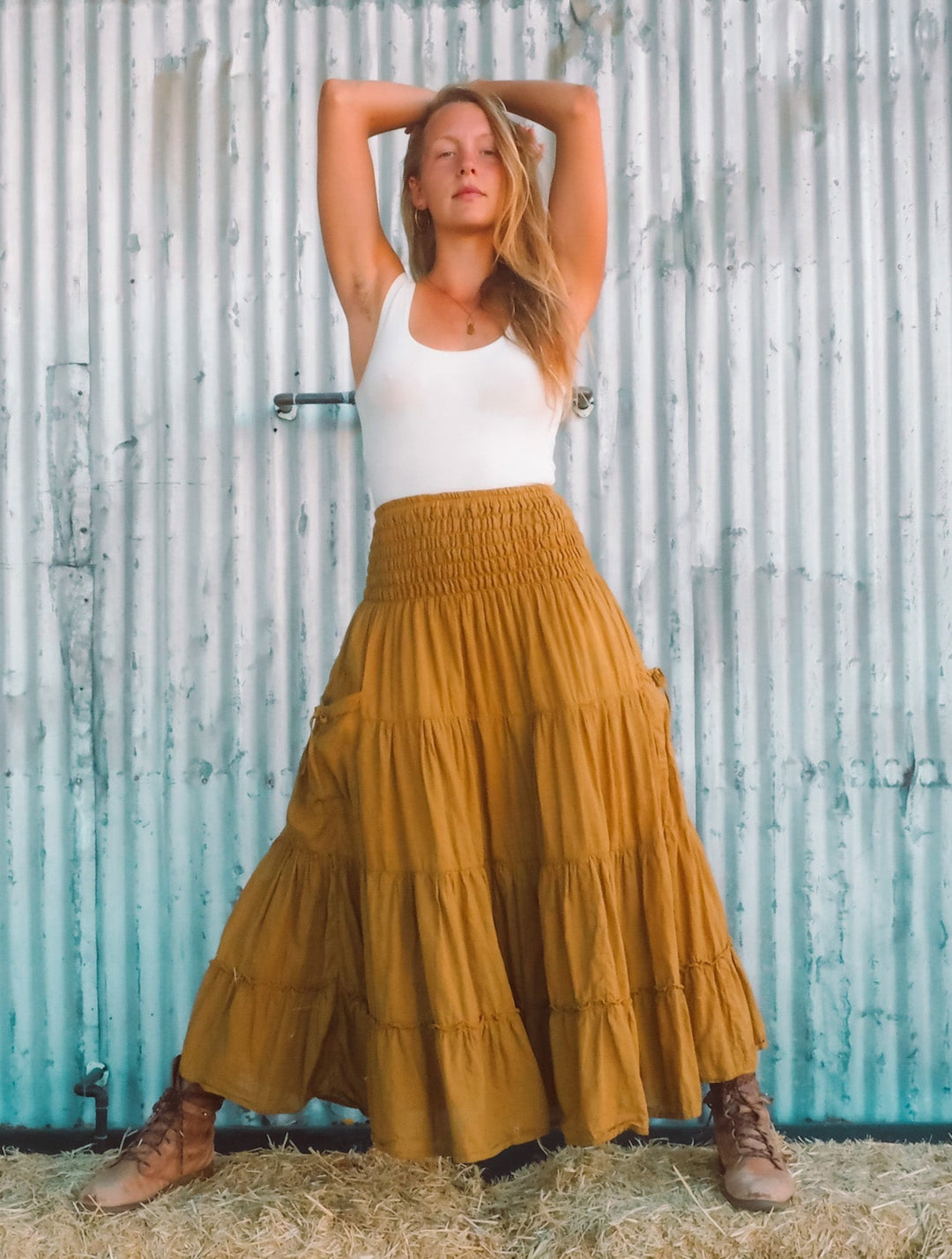 Woman is dressed in long ruffle skirt with white tank top tucked in.