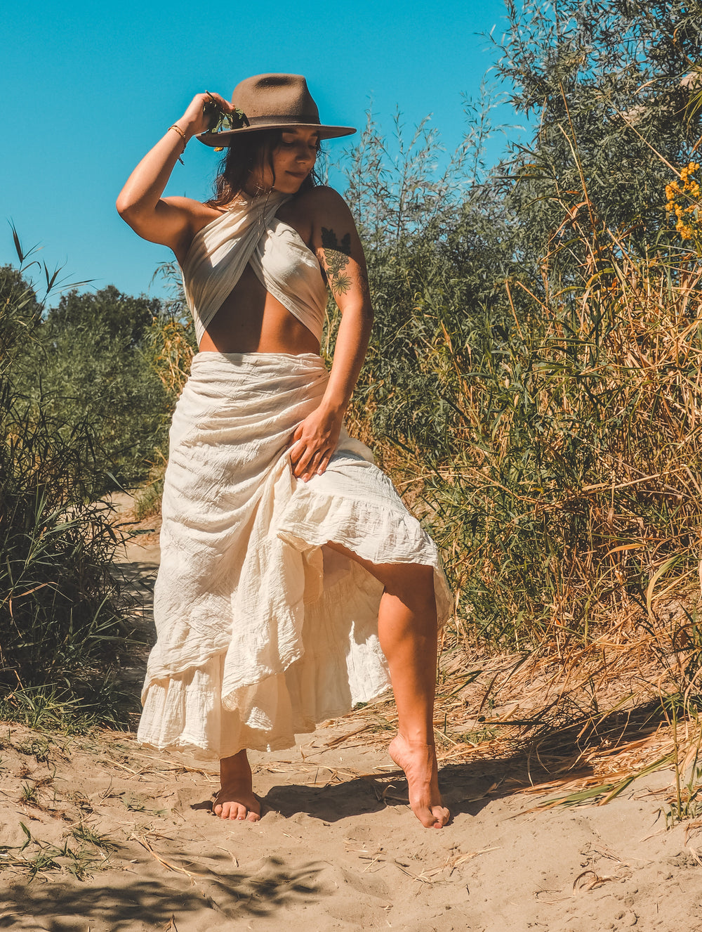 Model stands in sand dune adorned in cotton gauze midi skirt and matching wrap top.