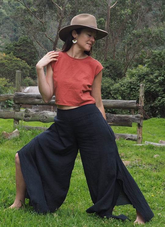 Model poses in red top and gauzy black pants.