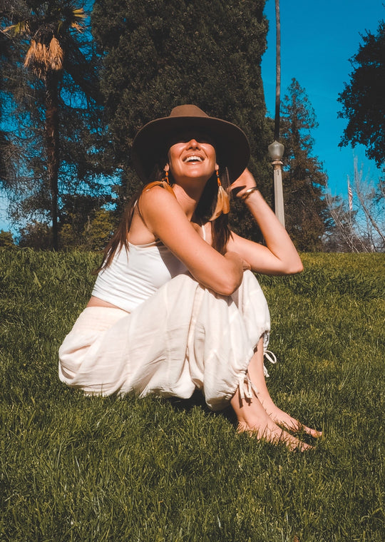 Model has on white top and white wide leg pants. Her hat keeps the sun out of her eyes.