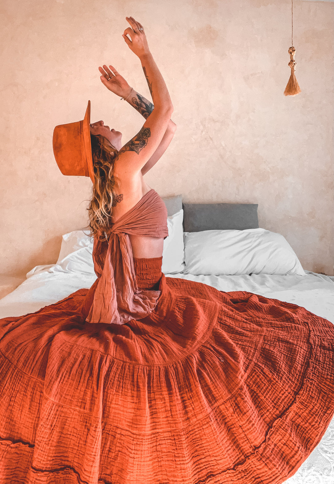 Model on bed in orange gauze Sophia tiered skirt