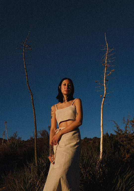 Model against night sky wears white crop top and un-dyed white skirt.