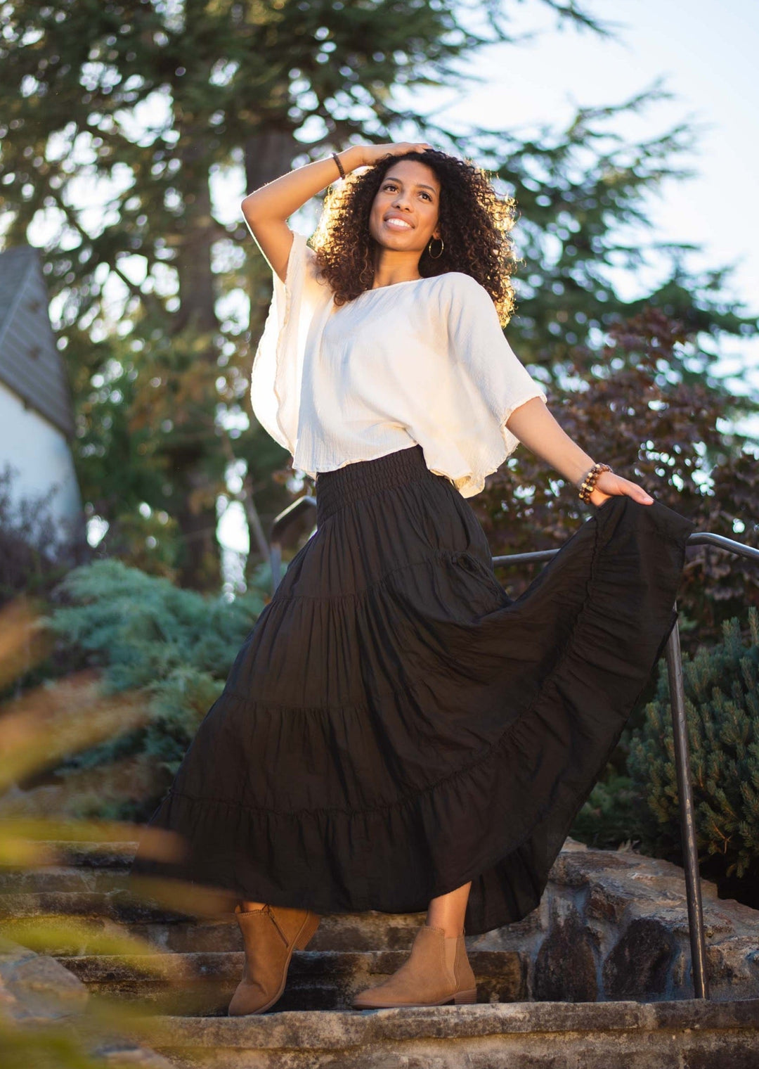 Female model is wearing loose white t-shirt paired with long black tired skirt.