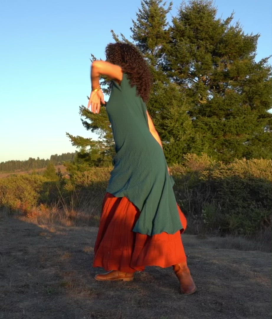 Female model dances in green gauze dress layered over maxi skirt.