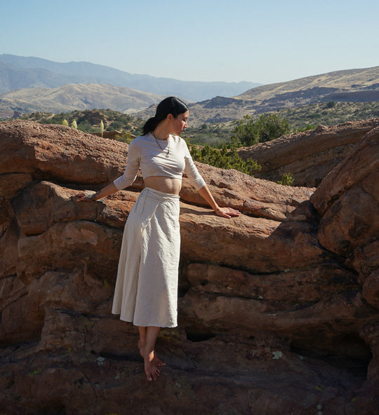 Female clothing model is dressed in long white skirt and white shirt.